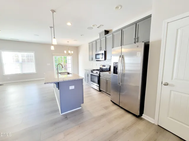 a kitchen with stainless steel appliances granite countertop a refrigerator a sink a stove and a wooden floors