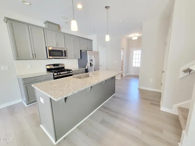 a kitchen with stainless steel appliances a sink a stove a microwave a center island and a refrigerator