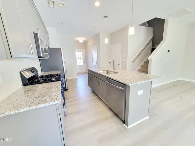 a kitchen with stainless steel appliances granite countertop a sink a stove and a refrigerator