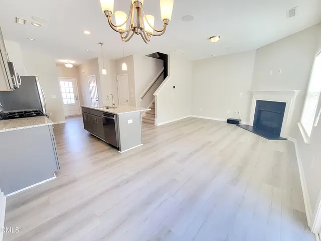 a living room with couches and kitchen view with wooden floor