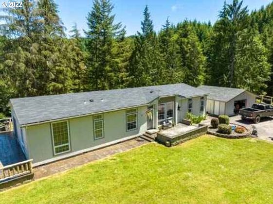 1578 Scholfield Road Reedsport, OR 97467 - Photo 30 of 37 a view of a backyard with table and chairs under an umbrella with wooden fence