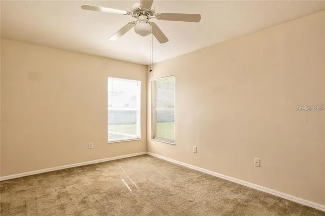 an empty room with windows and fan