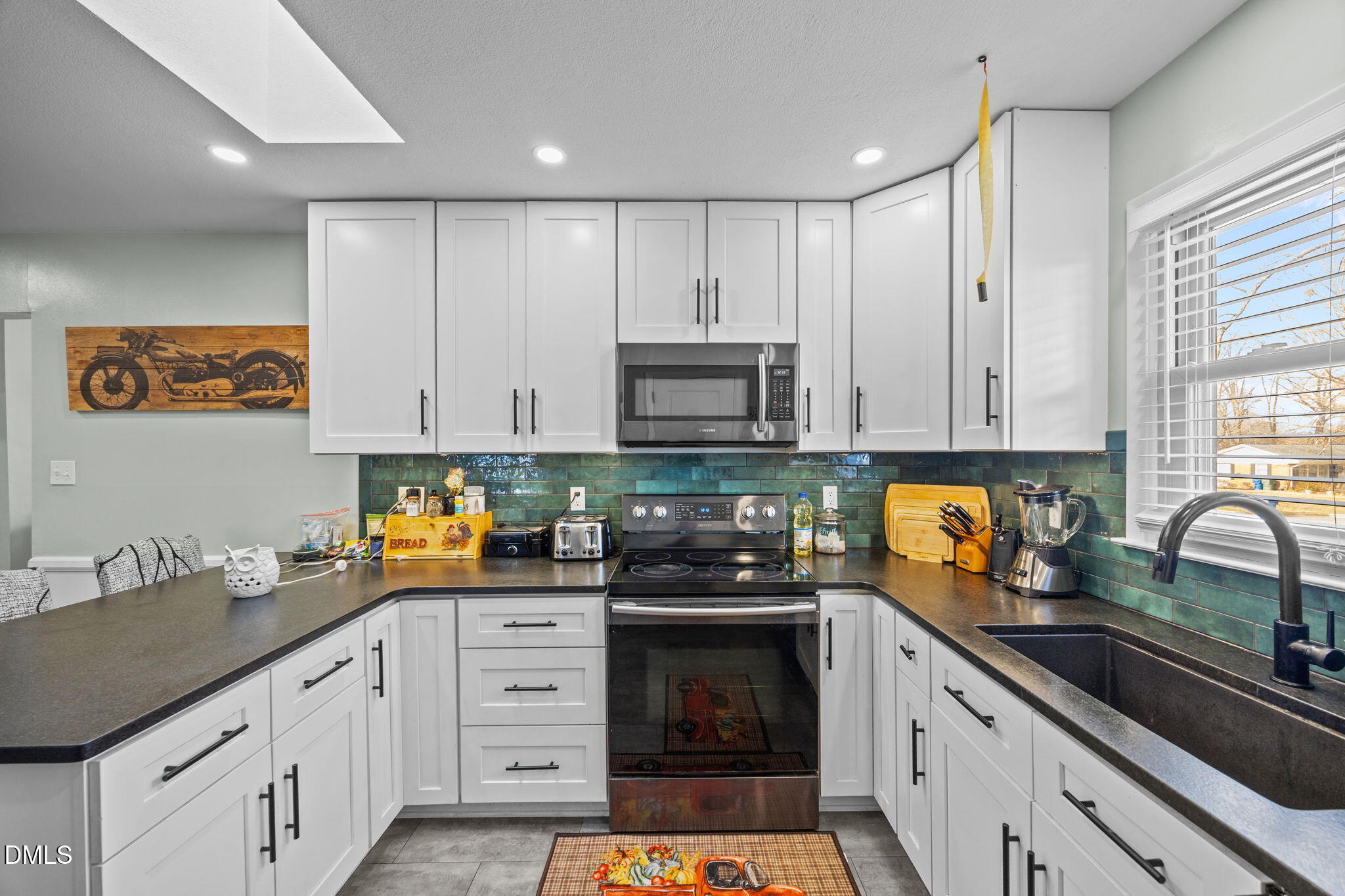 317 Clapp Street Graham, NC 27253 - Photo 10 of 33 a kitchen with stainless steel appliances granite countertop a stove a sink dishwasher and white cabinets with wooden floor