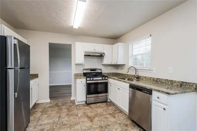 a kitchen with stainless steel appliances granite countertop a stove a sink and a refrigerator