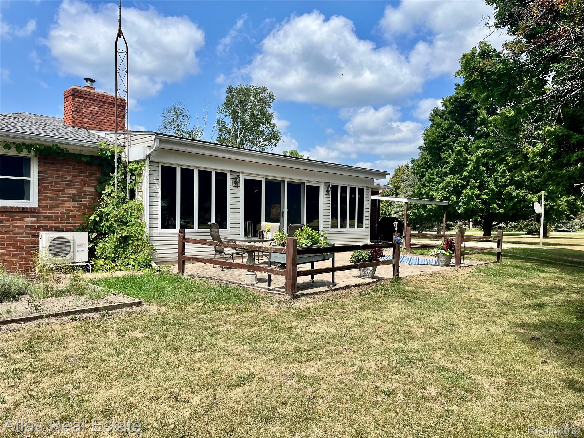 12026 Coolidge Road Goodrich, MI 48438 - Photo 8 of 56 Brick exterior with a sunroom addition featuring multiple windows, a paved patio area, and a fenced perimeter