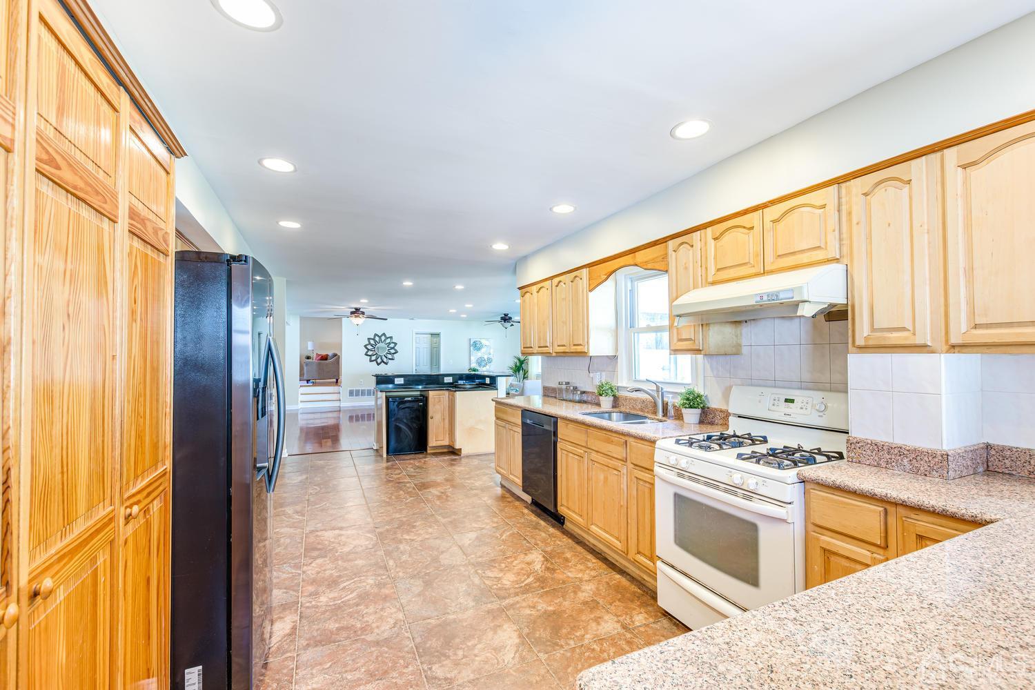 799 New Dover Road Edison, NJ 08820 - Photo 27 of 54 a kitchen with stainless steel appliances granite countertop a stove top oven a sink dishwasher a dining table and chairs with wooden floor