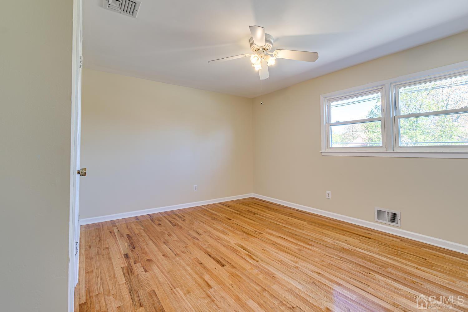 799 New Dover Road Edison, NJ 08820 - Photo 44 of 54 an empty room with wooden floor chandelier fan and windows