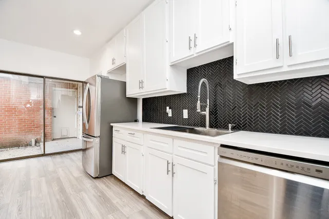 a kitchen with stainless steel appliances a stove top oven and a wooden floor