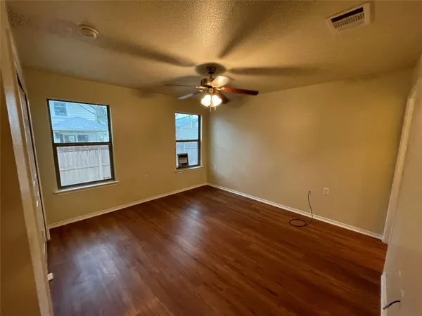 a view of an empty room with window and wooden floor