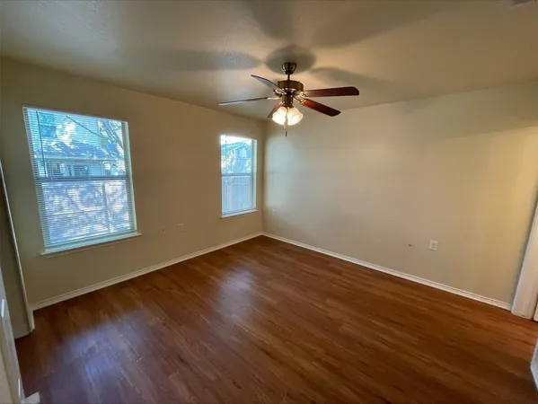 a view of empty room with wooden floor and fan