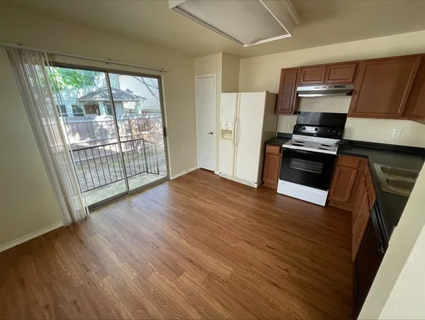a kitchen with granite countertop a refrigerator a stove a microwave and a wooden floor