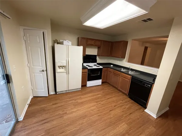 a kitchen with stainless steel appliances a refrigerator a sink a stove a microwave and wooden floors