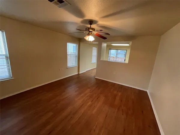 a view of an empty room with window and wooden floor
