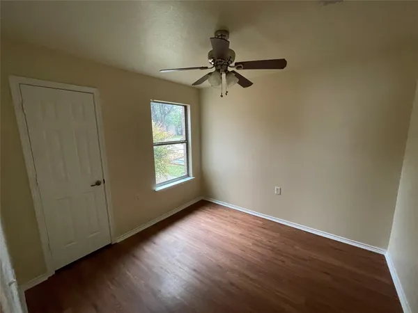an empty room with wooden floor cabinet and windows