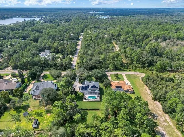 an aerial view of a house with a garden and lake