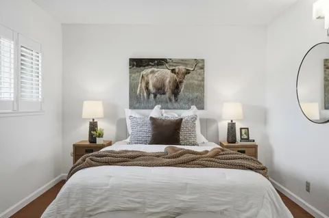 a bed sitting in a bedroom next to a window and a mirror