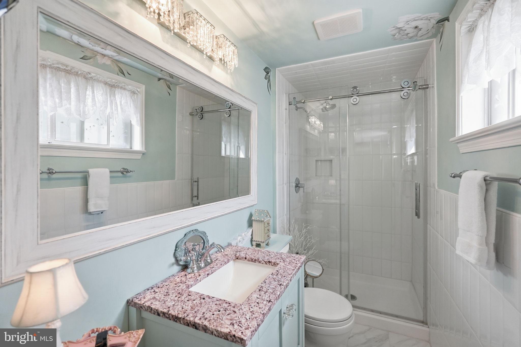 8406 Geneva Mason Road Potomac, MD 20854 - Photo 21 of 34 a bathroom with a granite countertop sink a toilet a mirror and shower