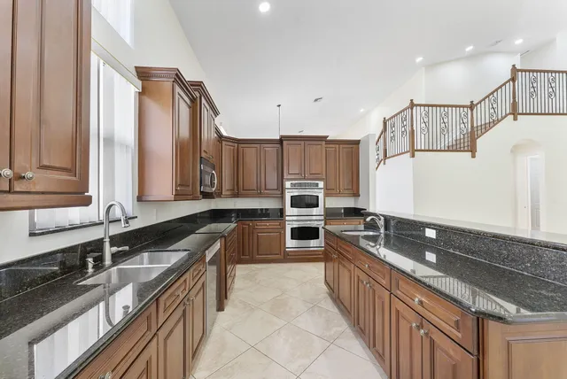 a large kitchen with granite countertop a sink and a stove top oven
