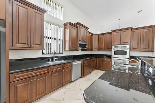 a kitchen with granite countertop a sink a stove counter space and cabinets