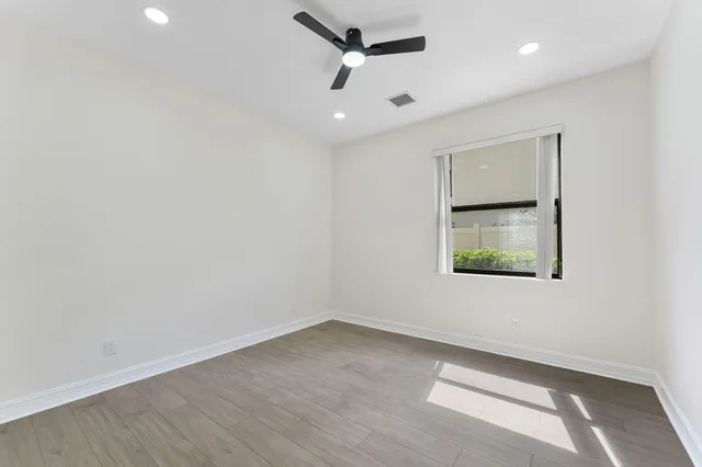 an empty room with a window and ceiling fan