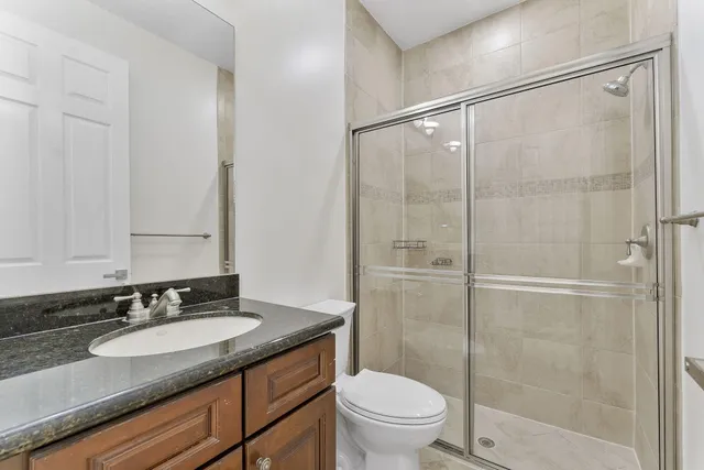 a bathroom with a granite countertop sink toilet and shower