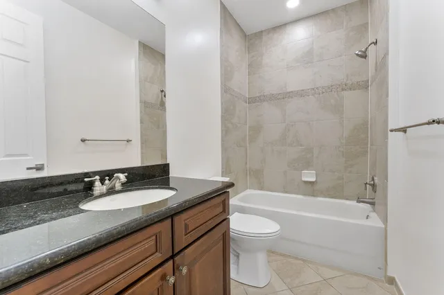 a bathroom with a granite countertop bathtub shower sink mirror vanity and toilet