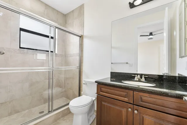 a bathroom with a granite countertop sink a toilet and shower