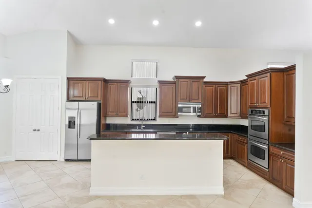 a kitchen with stainless steel appliances granite countertop a refrigerator a stove and a sink