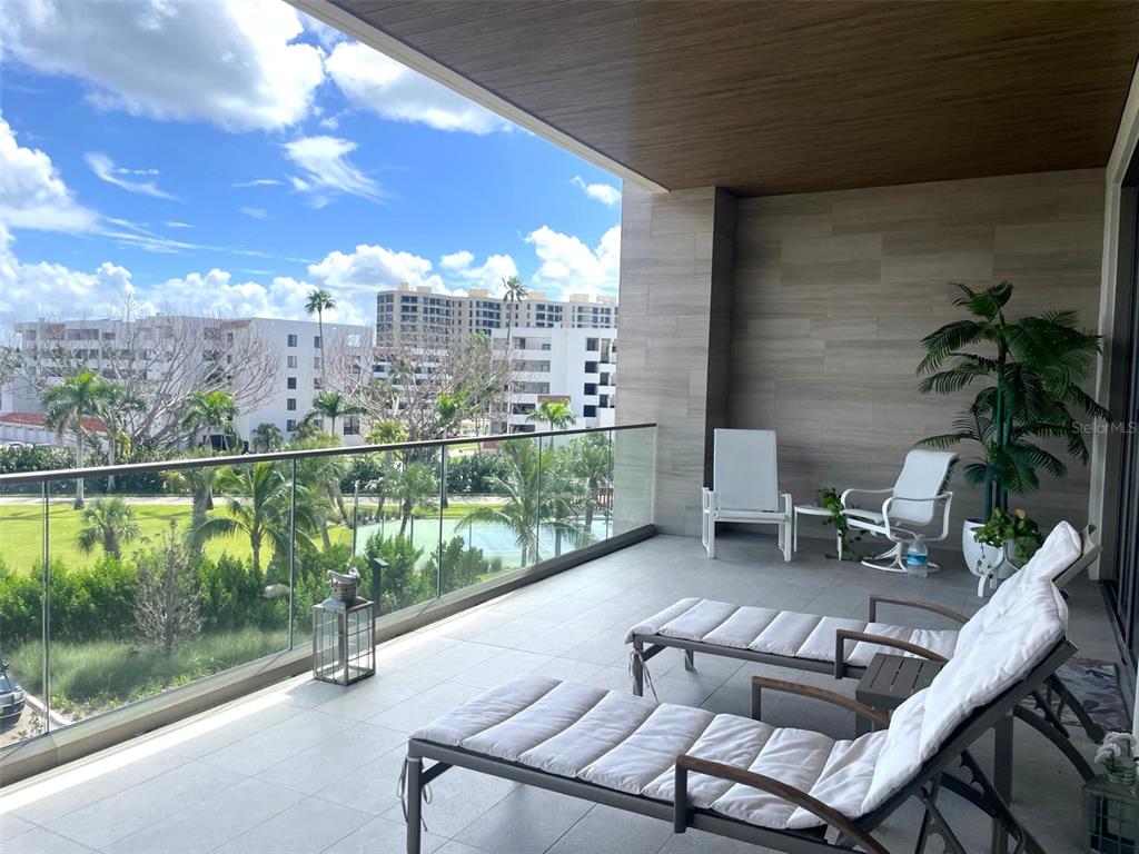 1581 Gulf Of Mexico Drive, Unit 307 Longboat Key, FL 34228 - Photo 38 of 83 a view of a chairs and table in patio with a yard