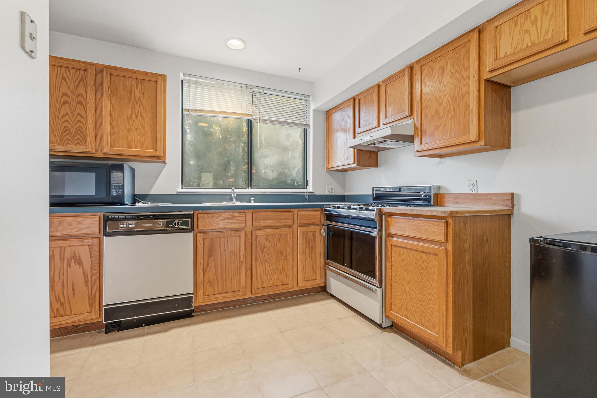 6 Stone Ridge Court, Unit 29 Baltimore, MD 21239 - Photo 8 of 26 a kitchen with stainless steel appliances granite countertop a stove a sink and white cabinets with wooden floors
