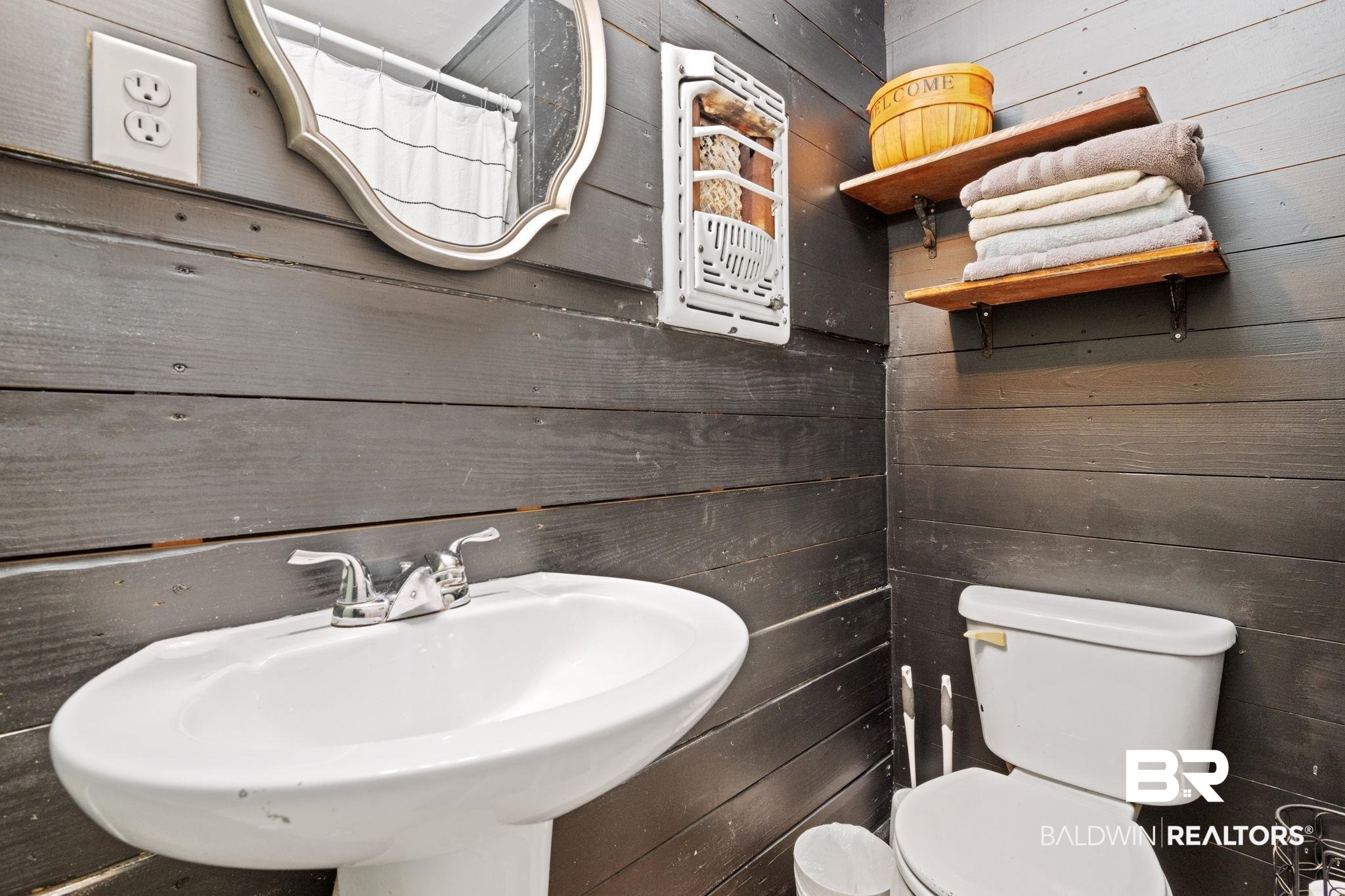 305 Alpine Street Mobile, AL 36611 - Photo 11 of 21 Bathroom featuring toilet, wooden walls, and sink