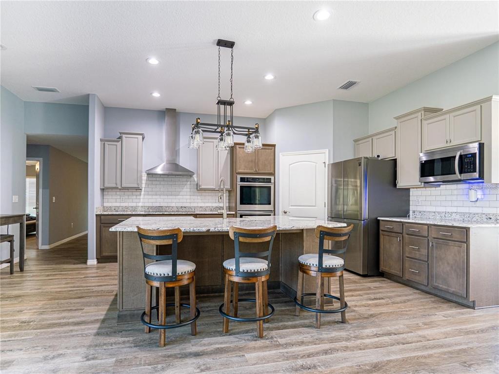 10688 Southwest 129th Terrace Road Dunnellon, FL 34432 - Photo 9 of 35 a kitchen with stainless steel appliances kitchen island granite countertop a table chairs microwave and sink