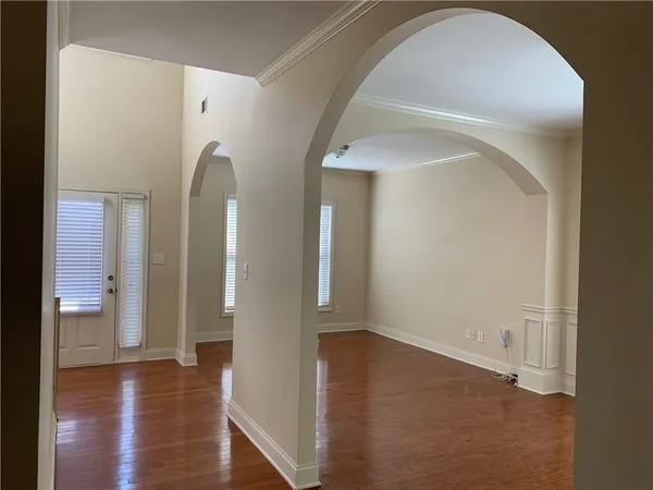 a view of an empty room with wooden floor and a bathroom