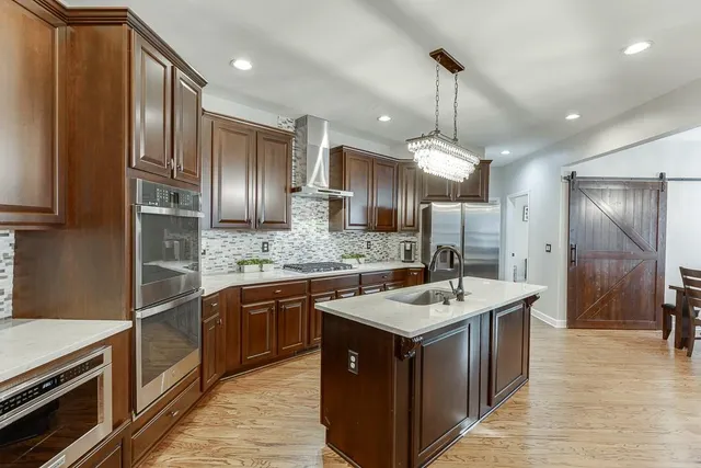 a kitchen with stainless steel appliances granite countertop a sink a stove a refrigerator and island