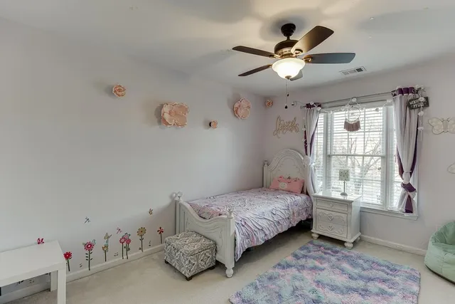 a bedroom with a bed couch chandelier and a window