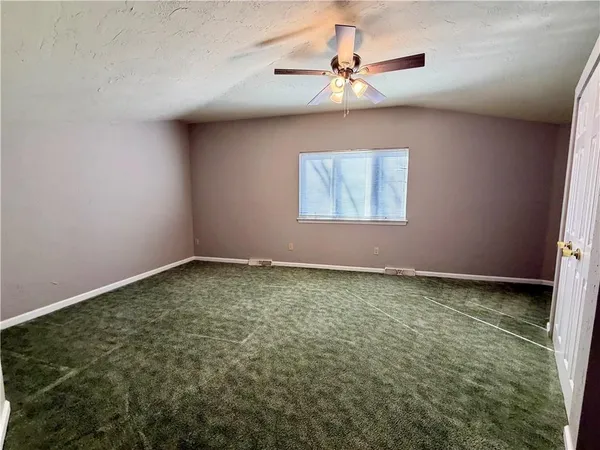 an empty room with a window and a ceiling fan