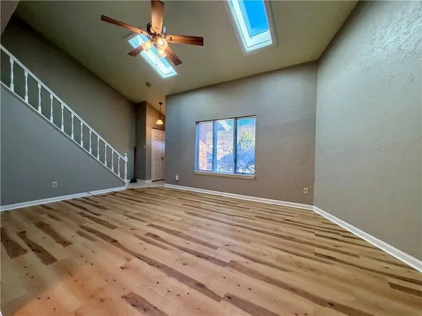 a view of empty room with wooden floor and fan