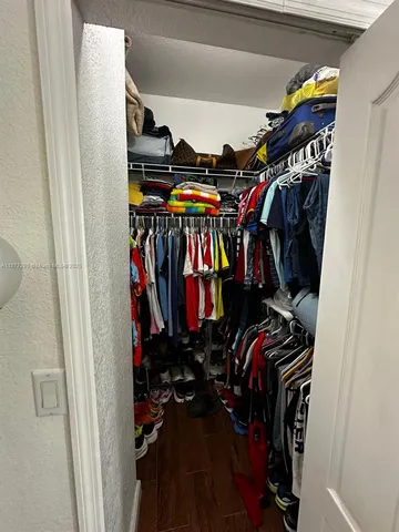 a view of walk in closet with clothes and shoes
