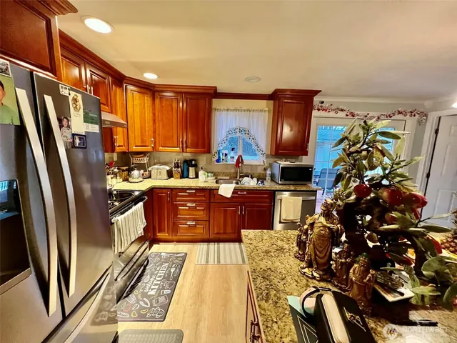 a kitchen with stainless steel appliances granite countertop a refrigerator a stove a sink and a dining table