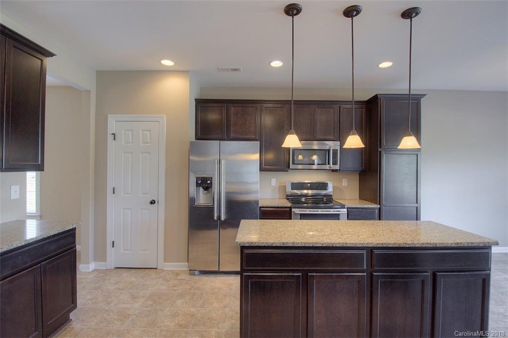 2001 Spring Rose Lane Wesley Chapel, NC 28104 - Photo 19 of 36 a kitchen with stainless steel appliances a sink a refrigerator a center island a stove and cabinets