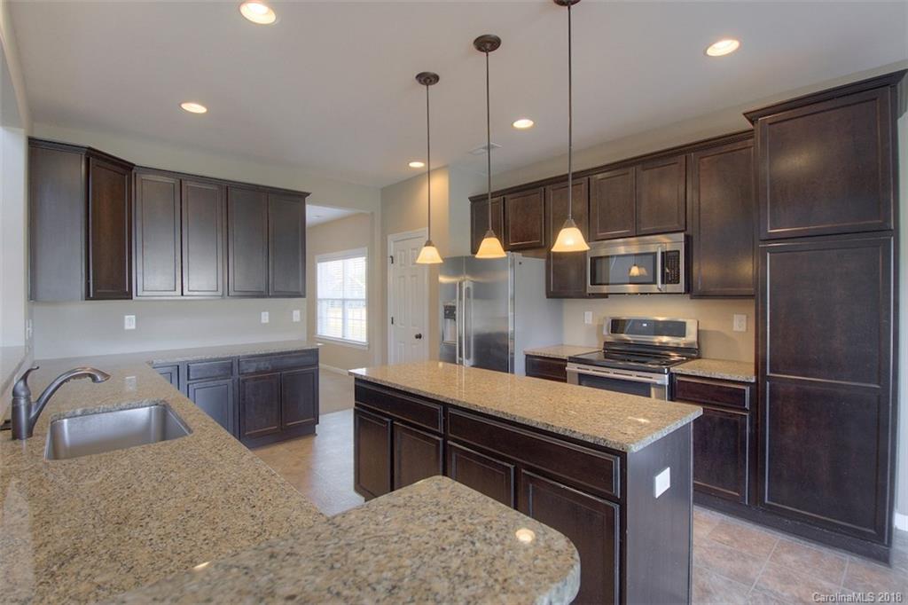 2001 Spring Rose Lane Wesley Chapel, NC 28104 - Photo 23 of 36 a kitchen with a refrigerator a sink and wooden cabinets