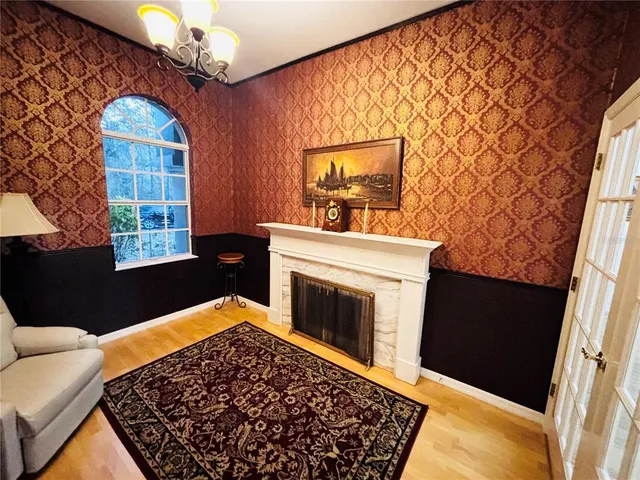 a view of a livingroom with a fireplace wooden floor and chandelier