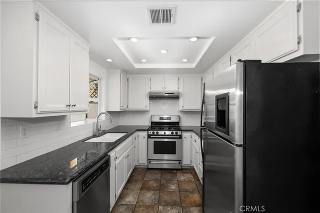 a kitchen with granite countertop white cabinets and stainless steel appliances