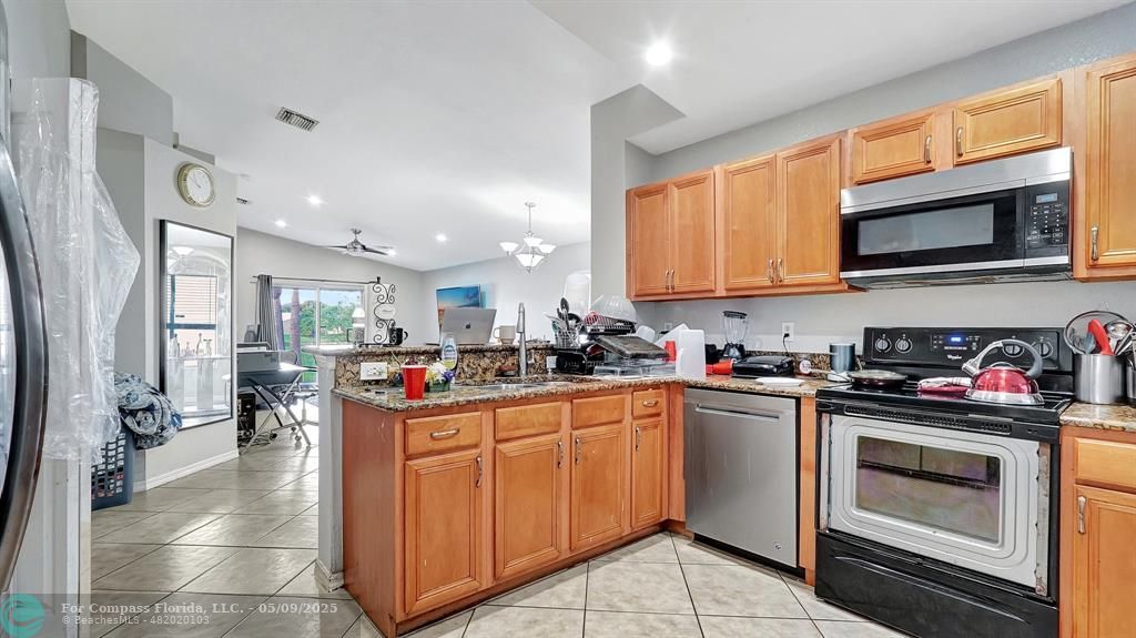 4558 Southwest 125th Lane Miramar, FL 33027 - Photo 15 of 47 a kitchen with stainless steel appliances granite countertop a stove top oven a sink dishwasher and cabinets with wooden floor