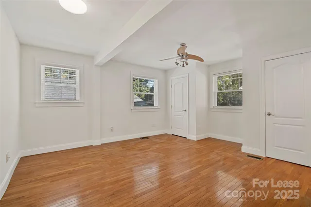 a view of empty room with wooden floor and fan