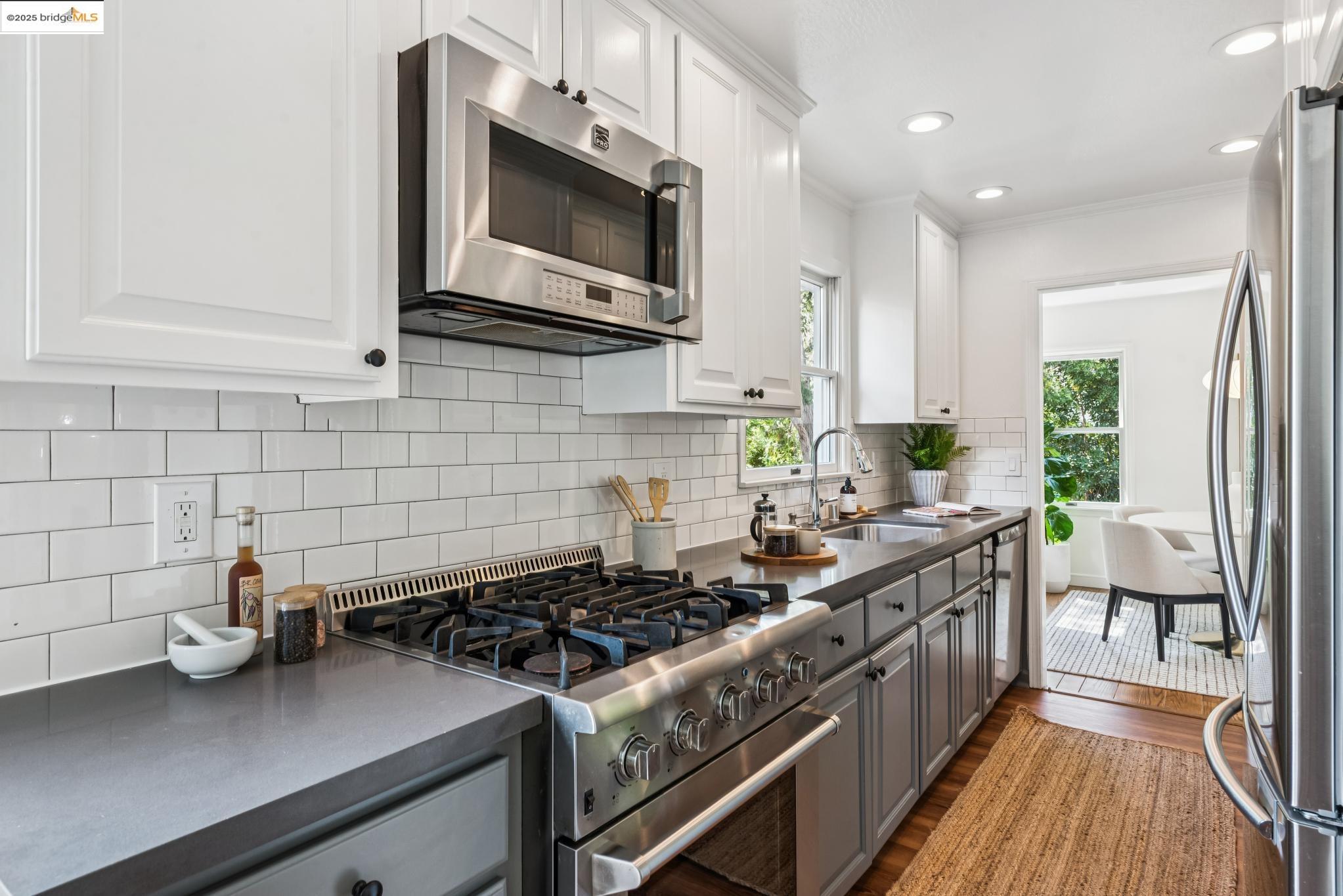 4479 Elinora Avenue Oakland, CA 94619 - Photo 16 of 47 Kitchen with appliances with stainless steel finishes, dark countertops, white cabinets, dark wood-type flooring, and crown molding