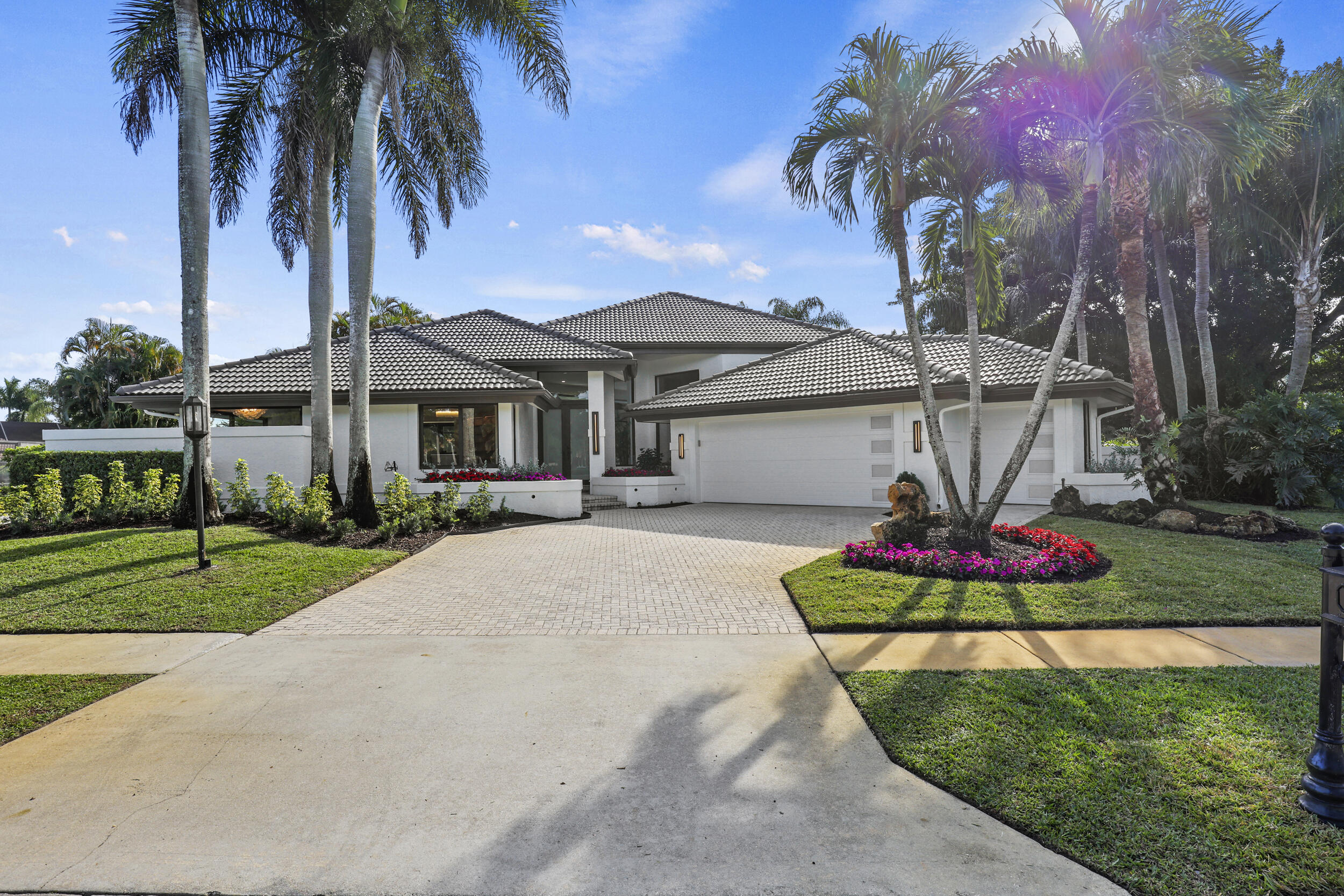 a front view of a house with a garden and trees