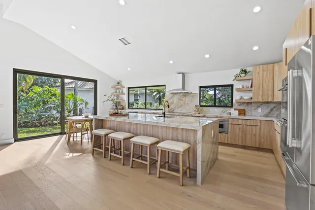 a large white kitchen with wooden floor and stainless steel appliances