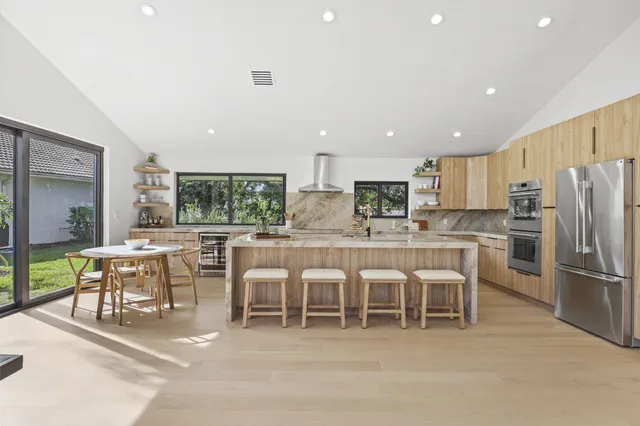 a kitchen with stainless steel appliances kitchen island granite countertop a table and chairs