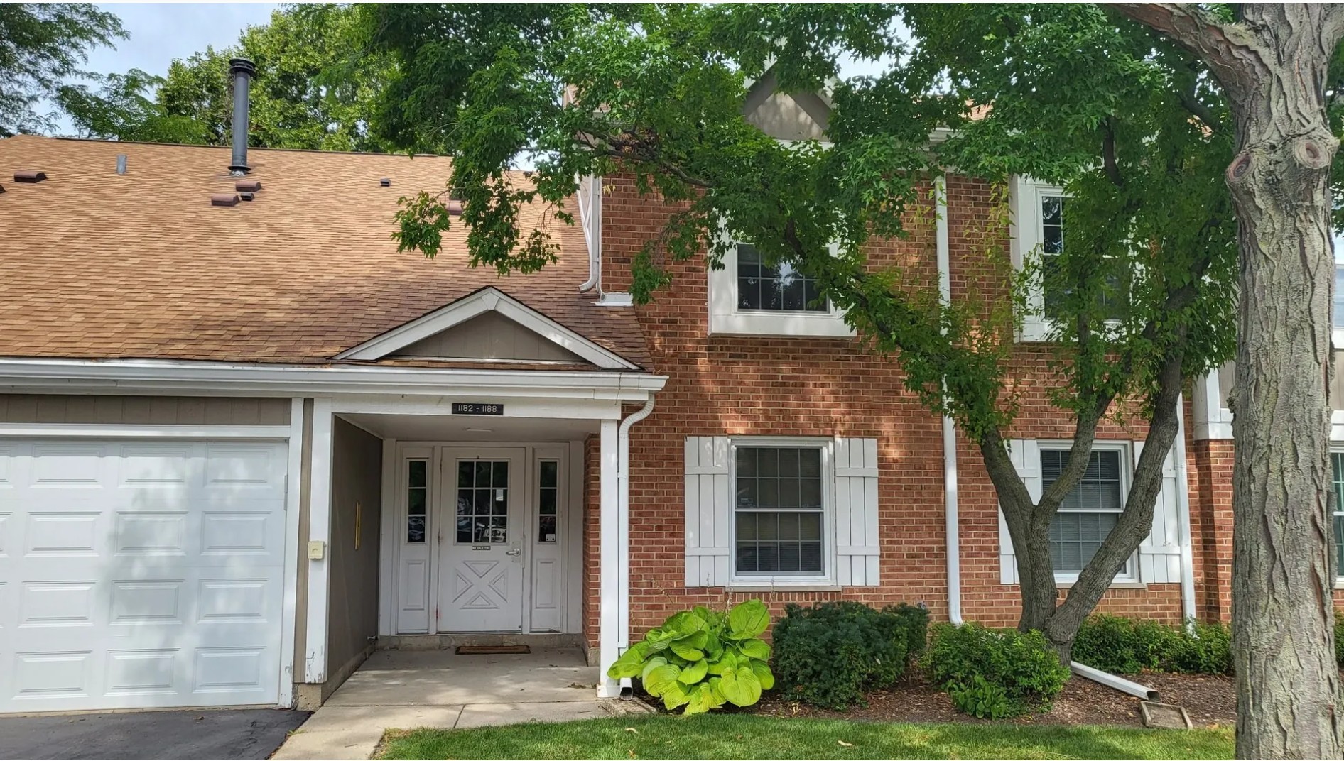 1186 Auburn Lane, Unit 1186 Buffalo Grove, IL 60089 - Photo 1 of 23 front view of a house with potted plants and a large tree